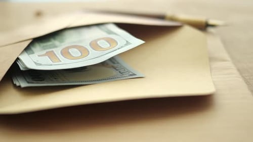 Dinero en efectivo en un sobre sobre una mesa con un bolígrafo para notas