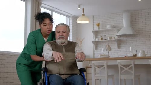 Woman Helping Senior Man in Wheelchair Exercise