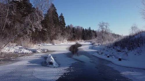 Winter partially frozen river in forest landscape aerial view