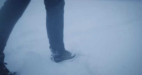 Hiker walk in deep fresh snow during snowfall, feet close up