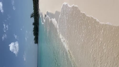 The sea waves of turquoise waters reaching the white sand of the coast