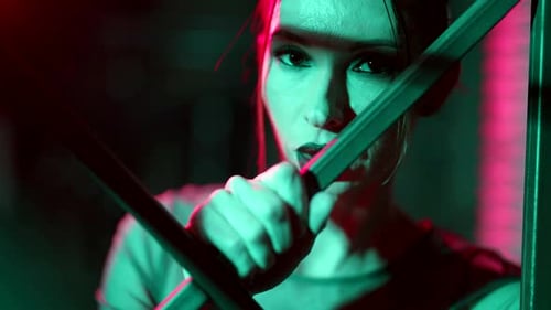 Woman Gripping Metal Bars in Colorful Lighting