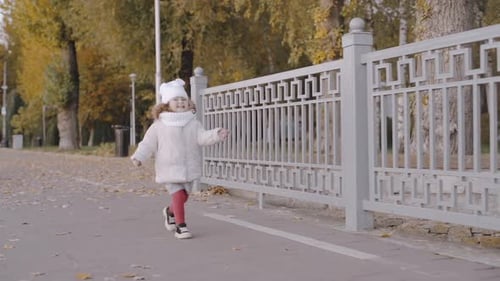 Child running in the autumn park in warm sunny day, slow-motion