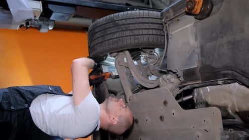 Mechanic Inspecting Undercarriage of Car in Auto Repair Shop
