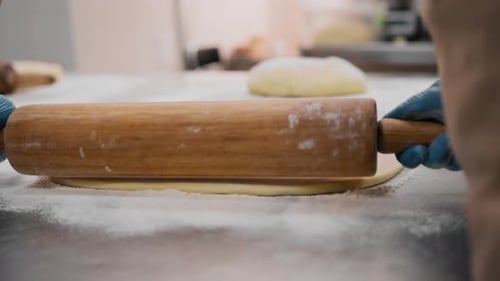 The kitchen in the bakery - the process of preparing cinnabons, the woman baker forms doughs