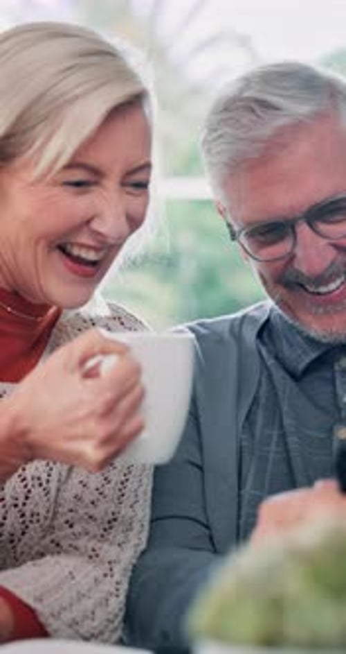 Smiling Couple Laughing Looking at Device Indoors