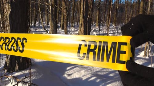 Gloved Hands Unrolling Crime Scene Tape in Snowy Forest Investigation Setup