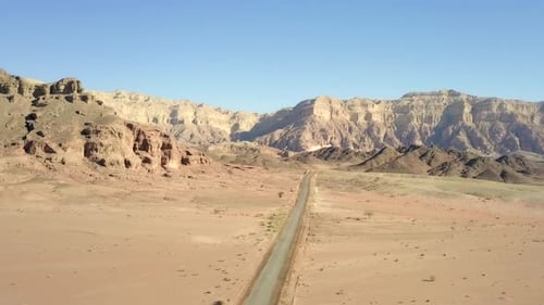 Empty desert road with mountains and blue sky in the background