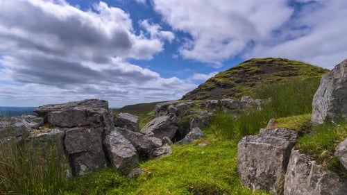 Time lapse of rural landscape with rocks in the foreground in grass hillside on a spring sunny day