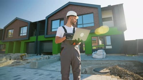 Builder with Laptop Inspecting Townhouse Construction