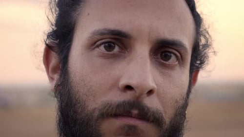 Close Up Portrait of Young Caucasian Man with Beard Looking at Camera with Serious Face