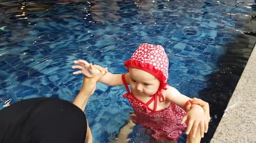 Süßes kleines Mädchen, das mit ihrer Mutter in einem Hallenbad schwimmen lernt. - High Angle