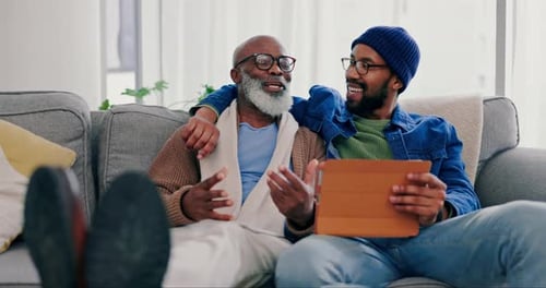 Senior and Young Adult Relax Together With Tablet