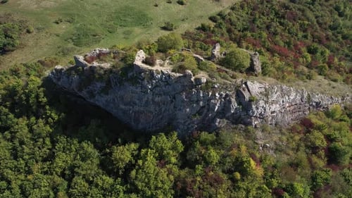 Aerial view of medieval fortification ruins, on a cliff in the forest by drone