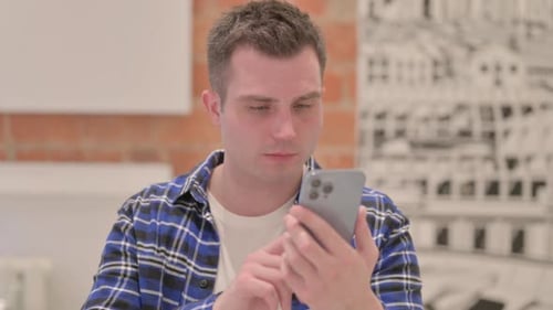 Young Adult Using Smartphone in Brightly Lit Room