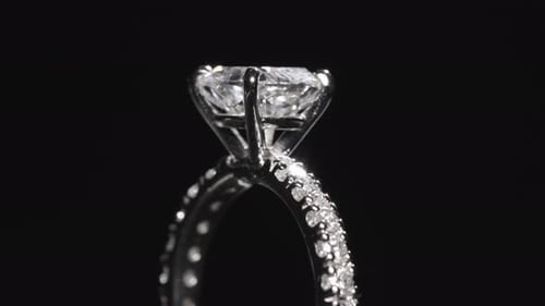 Close up, diamond engagement ring rotating against black studio background