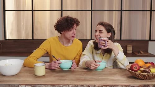 Couple Laughing Together at Breakfast in Kitchen
