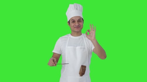 Happy Indian professional chef tasting food and showing okay sign Green screen