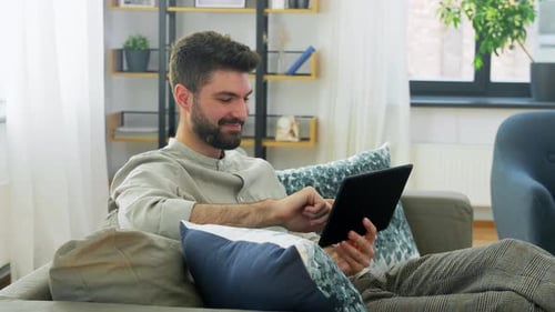 Man relaxing on sofa using his tablet device