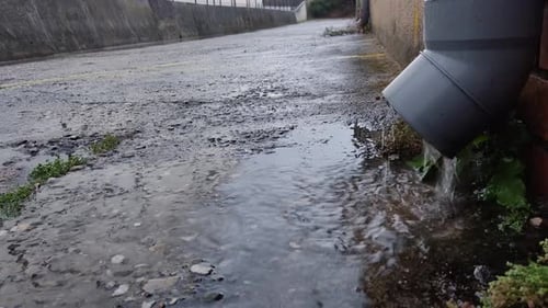 Vue de l'eau de pluie tombant dans la rue depuis un tuyau d'un bâtiment après une tempête.