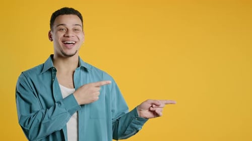Smiling Young Guy Looking to Empty Place for your Advertising Recommending Man Pointing at Right
