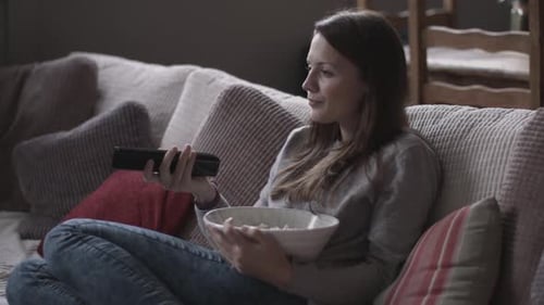 Woman Relaxing on Couch Eating Popcorn and Watching TV