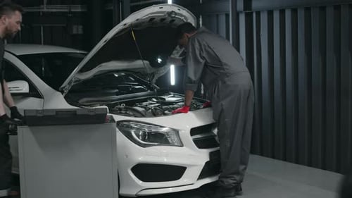Three Diverse Mechanics Working on Customers Car in Garage