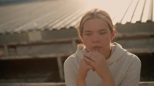 Contemplative Woman Sitting on Rustic Stadium Bleachers in Reflective CloseUp