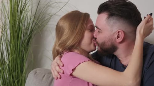 Affectionate Couple Embracing and Kissing on Couch