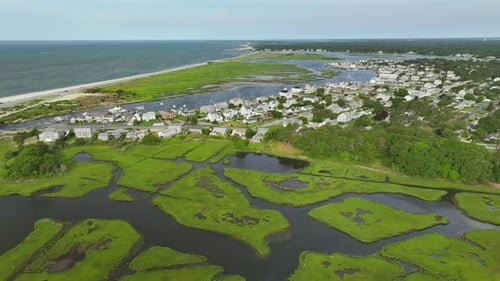 Expansive view of lush green marshland, Atlantic ocean in Cape Cod, idyllic charming homes, aerial p