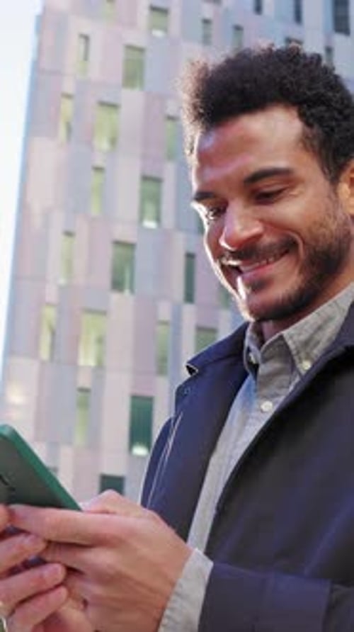 Smiling Young Businessman Using Smartphone in City