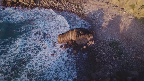 Golden Hour Drone Footage of Waves Crashing Against Rocky Cliffs