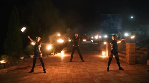 Feueraufführungsshow Künstler drehen nachts brennende Stangen im Freien, Stammestanz im Freien mit Flammen, Mann und