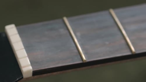 Guitar Nut And Frets On The Fingerboard On An Acoustic Guitar. - rack focus shot