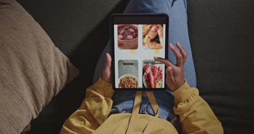 Woman searching for fast food website with tablet. Person browsing online menu from delivery app
