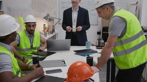 Construction Team Meeting with Engineer Reviewing Plans in Office