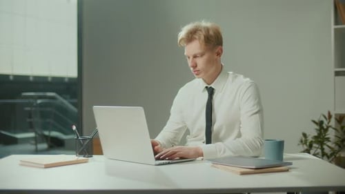 Young Adult Typing on Laptop in Office Environment
