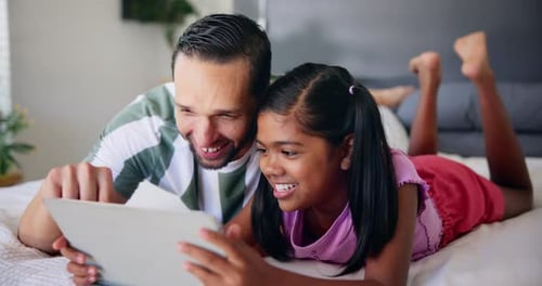 Father and Daughter Using Tablet Device on Bed