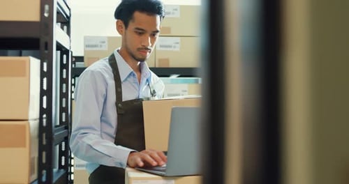 Asian business partner man use laptop computer check inventory online stock data program.