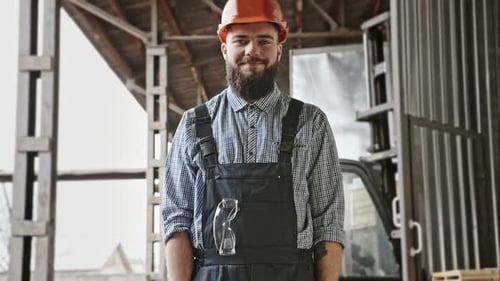 Portrait of Cheerful Bearded Handsome Young Adult Industrial Engineer Wear Plastic Helmet Uniform