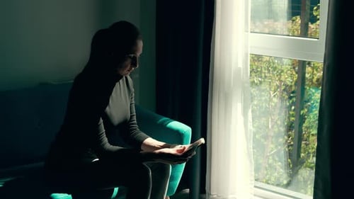 Woman Holding UK Cash and Planning Finances Near Bright Window in Modern Hotel Room Counting British