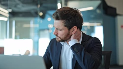 Businessman Suffering Neck Pain While Working In Office
