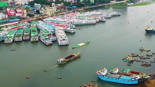 Colorful boats and ferries on a river near an urban area, aerial shot
