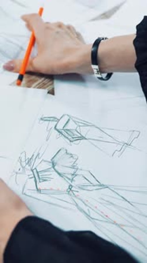 Fashion Designer Sketching Clothing Designs on Paper