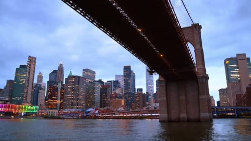 Travelling by the East River under the Brooklyn Bridge. Beautiful skyline of New York at backdrop.