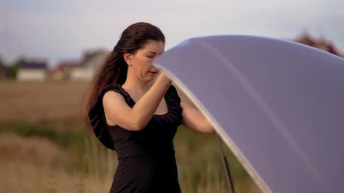 Woman Opening Car Hood and Becoming Desperate Because Her Vehicle Broke Down in Middle of Nowhere