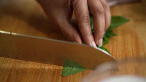 Cutting of edible leaves by sharp knife to be put on recipe.