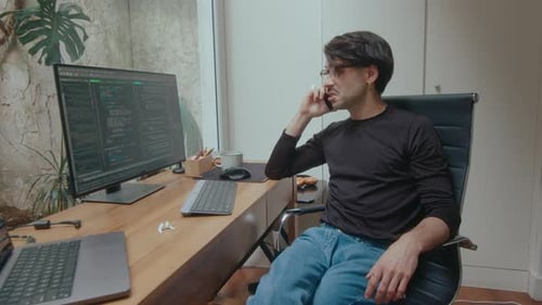 Computer Programmer Having Phone Conversation at Workplace