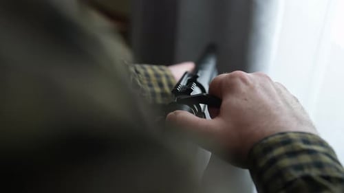Man Loads a Black Rifle Indoors Close Up