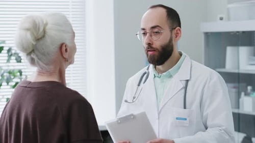Doctor Explaining Treatment Plan to Elderly Woman in Medical Office
